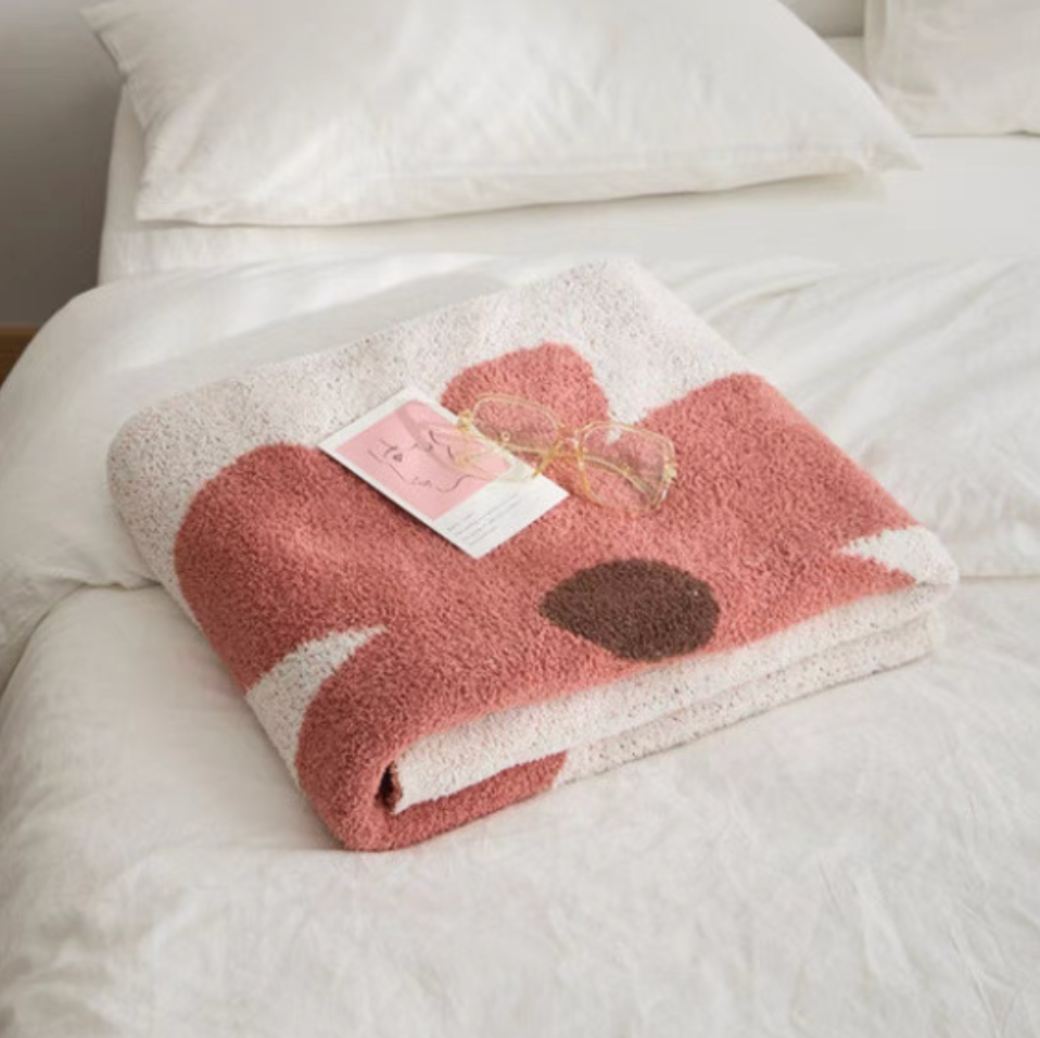 Floral letter chenille throw blanket folded on bed with soft plush texture and pink flower pattern