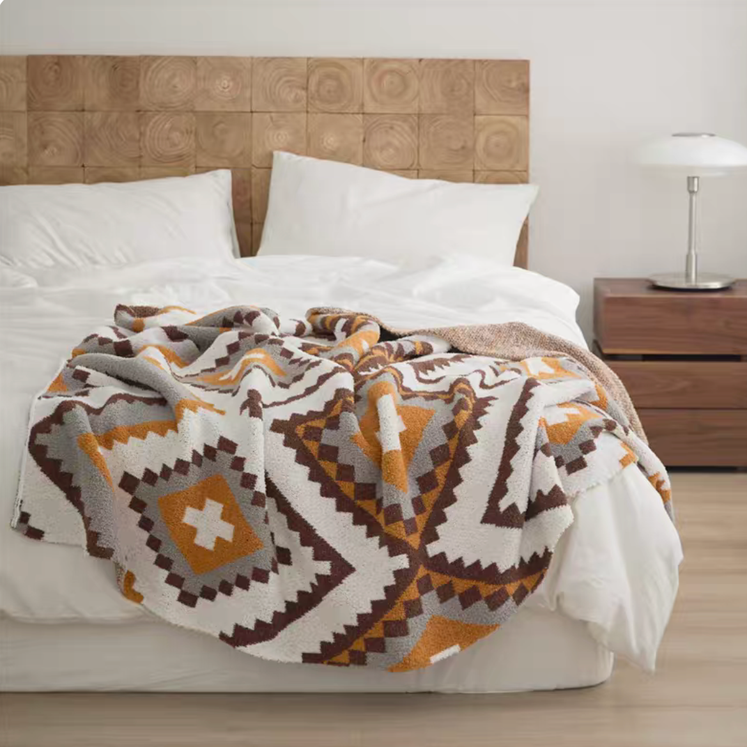 Kettle chenille throw blanket with brown and mustard geometric diamond pattern draped over bed
