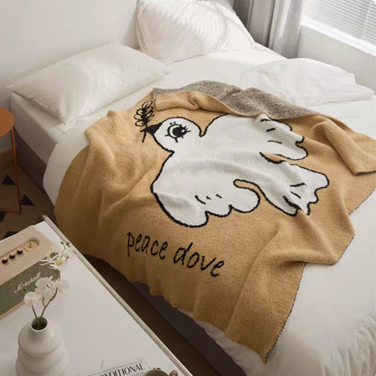 Peace dove chenille throw blanket featuring white dove illustration and text draped over bed