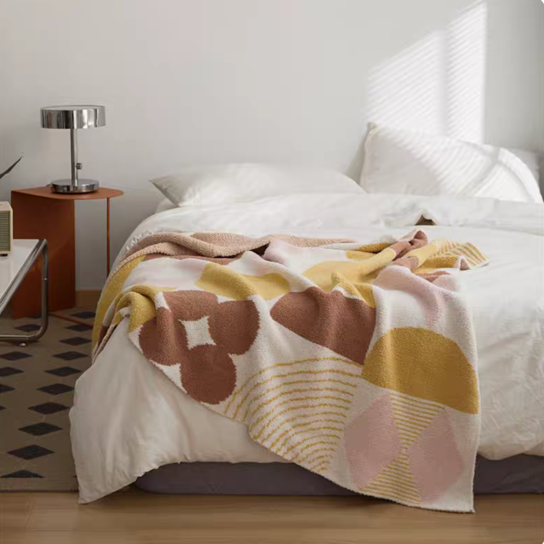 Romand chenille throw blanket with soft abstract floral and stripe pattern in warm neutral tones on bed