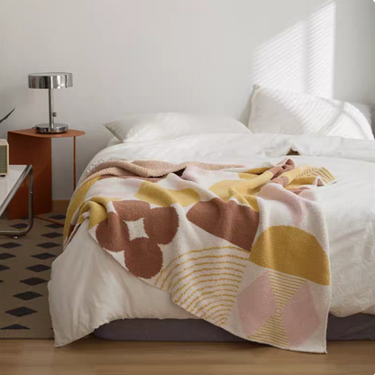 Romand chenille throw blanket with soft abstract floral and stripe pattern in warm neutral tones on bed