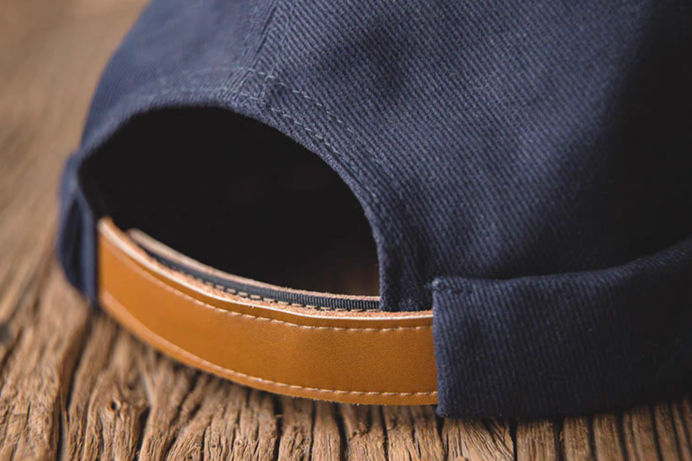 Close up of Dark Blue Nautical Miki Cap adjustable strap with leather detail and cotton fabric texture