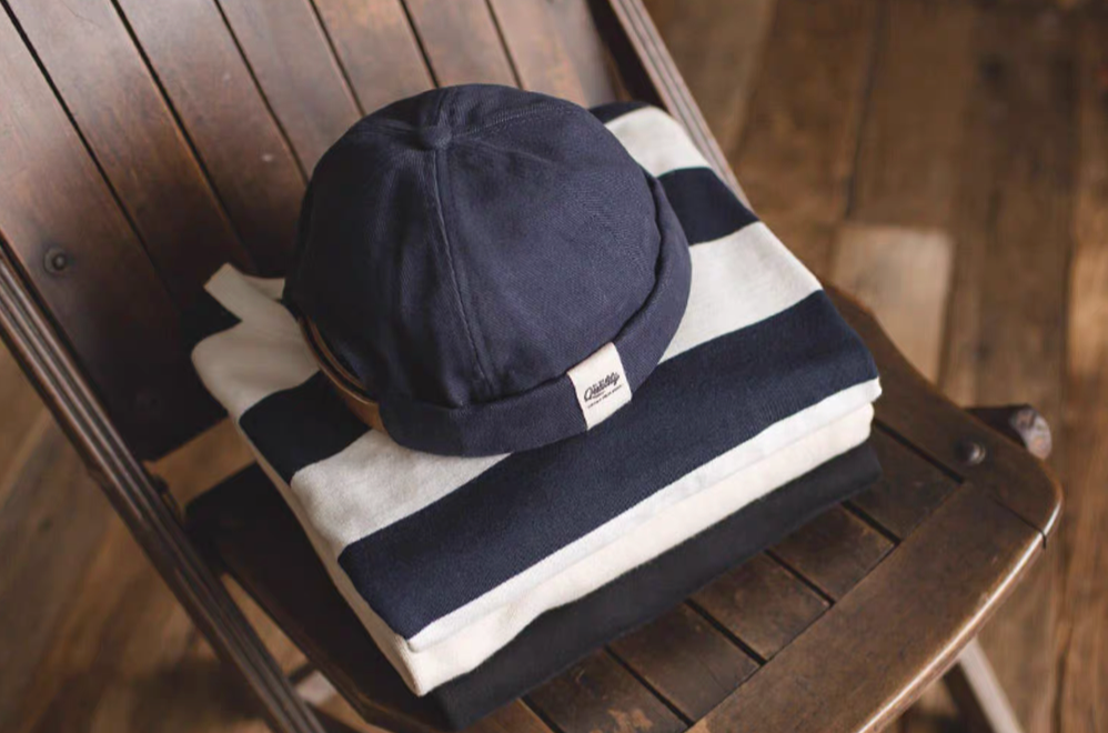 Dark Blue Nautical Miki Cap top view styled on striped garment showing round crown and compact brimless shape