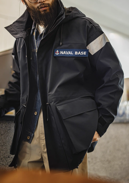 Close-up of model wearing navy reflective parka showing NAVAL BASE patch and utility pocket