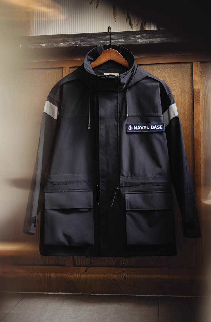 Navy reflective hooded parka hanging on wooden hanger showing reflective shoulder strips