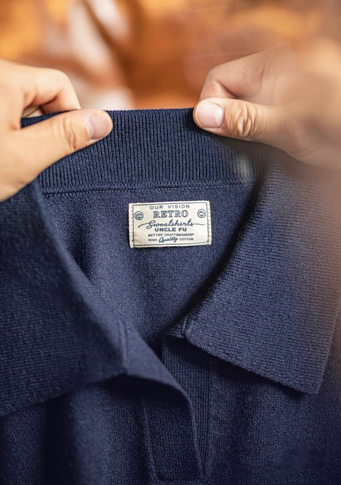 Close-up of brand tag and knit collar texture of navy blue polo sweater.