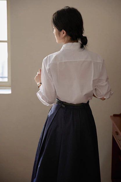 White embroidered relaxed shirt back view near window light highlighting smooth drape and tailored finish