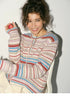 Beige cardigan with red and blue fair isle stripes close up smiling model holding apple showing soft knit texture