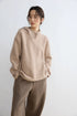 Model in Oatmeal snap-neck hoodie with hands in pockets, showing the slouchy oversized fit