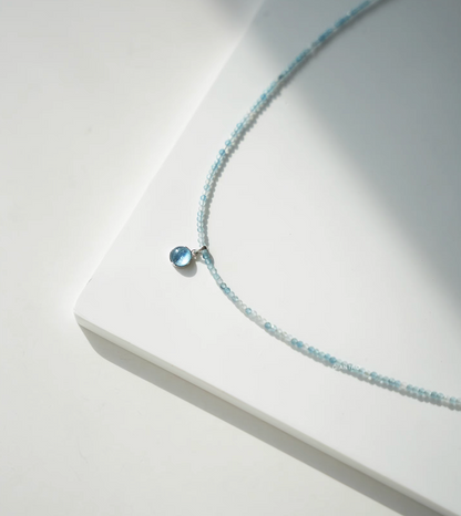 Close-up of Ocean Breeze aquamarine necklace featuring round aquamarine cabochon pendant on delicate blue beads