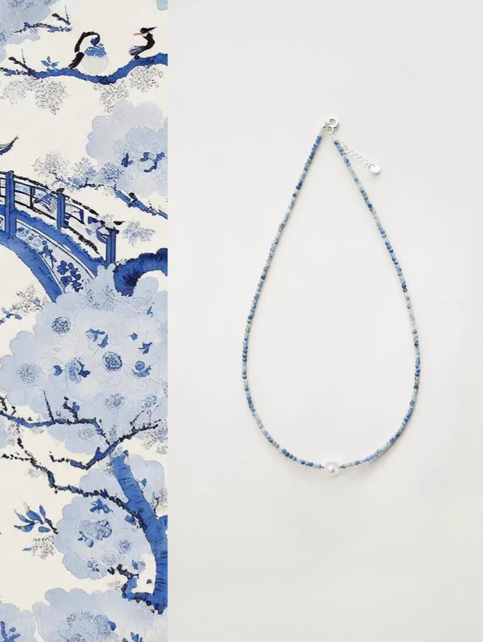 Ocean Whisper Pearl Necklace flat lay with blue sodalite beads and central freshwater pearl on neutral background