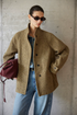 Front view of an Olive heathered wool tweed jacket showing the button front, patch pocket, and cuff tab