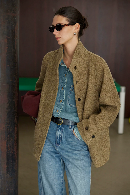 Olive wool tweed jacket worn open, showing the stand collar, dark buttons, and cuff tabs