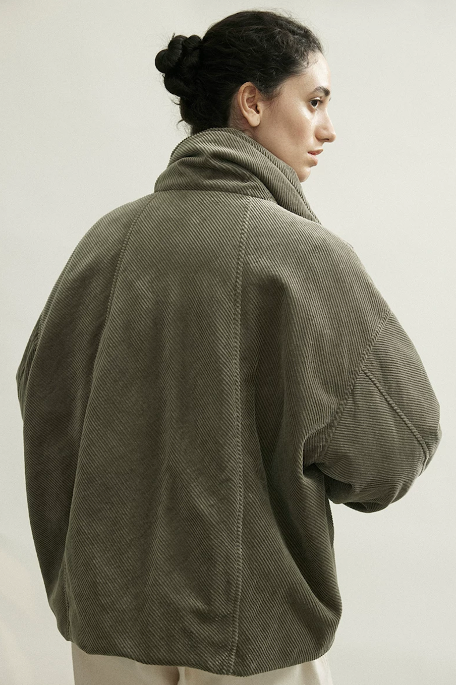 Back view of an Olive Gray bias-cut corduroy down jacket showing diagonal ribs and curved back seams