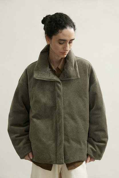 Front view of an Olive Gray boxy corduroy down jacket closed with a concealed placket
