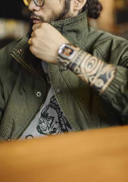 Model adjusting olive green M-65 jacket stand collar with drawstring detail