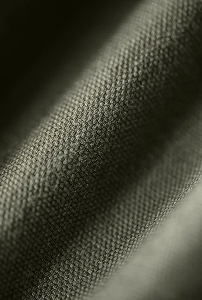 Close-up of olive green cotton fabric texture from M-65 utility jacket