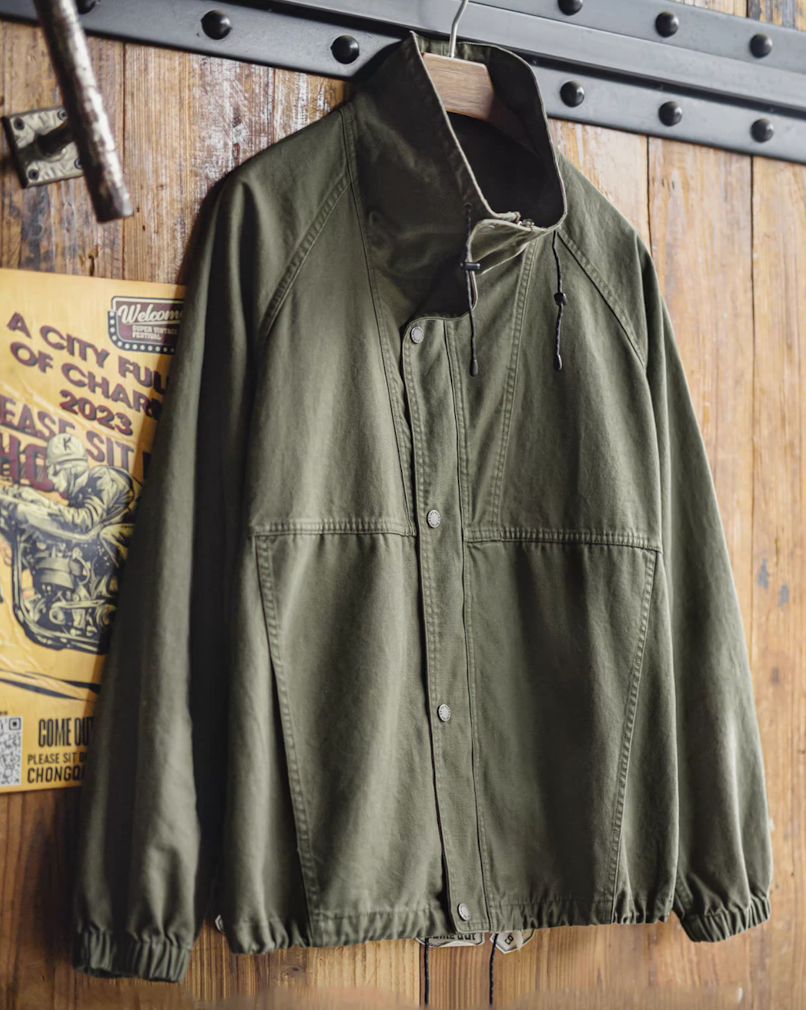 M-65 utility jacket hanging on wooden wall with vintage poster