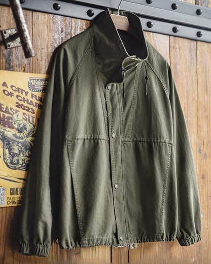 M-65 utility jacket hanging on wooden wall with vintage poster