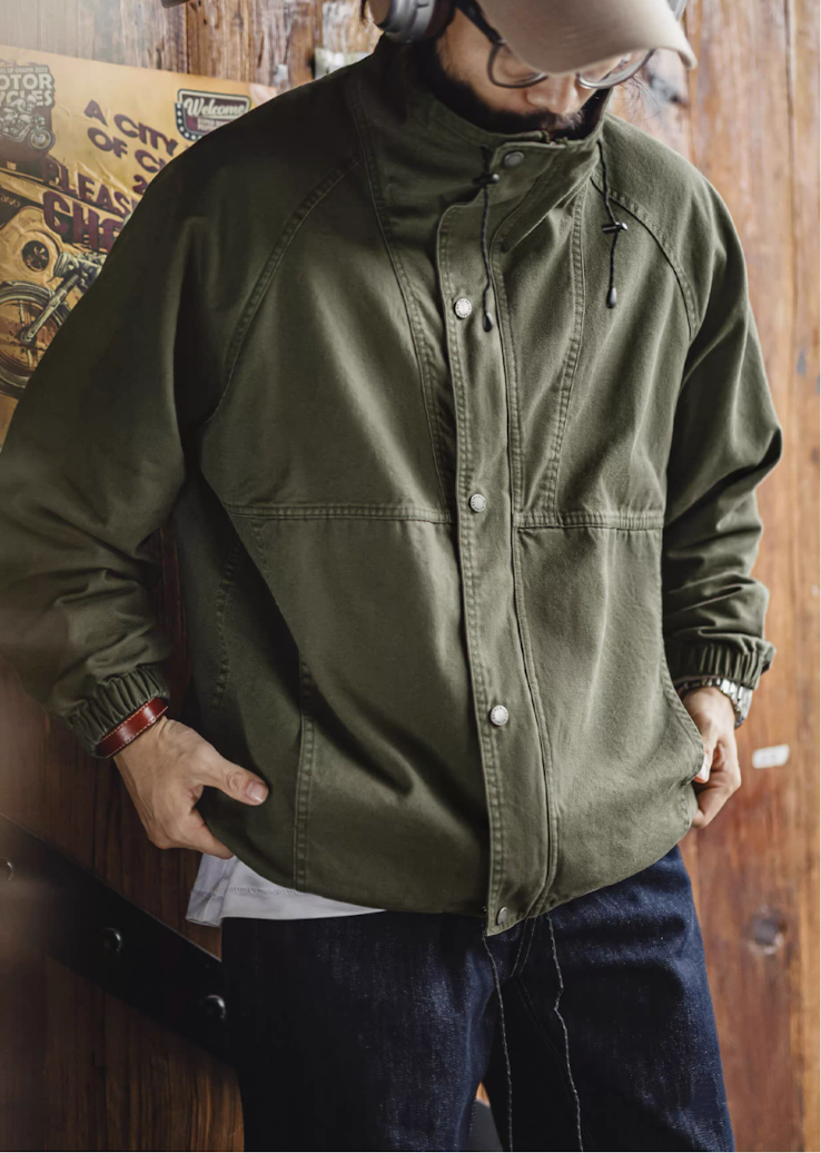 Model wearing olive green M-65 jacket with stand collar styled casually with jeans