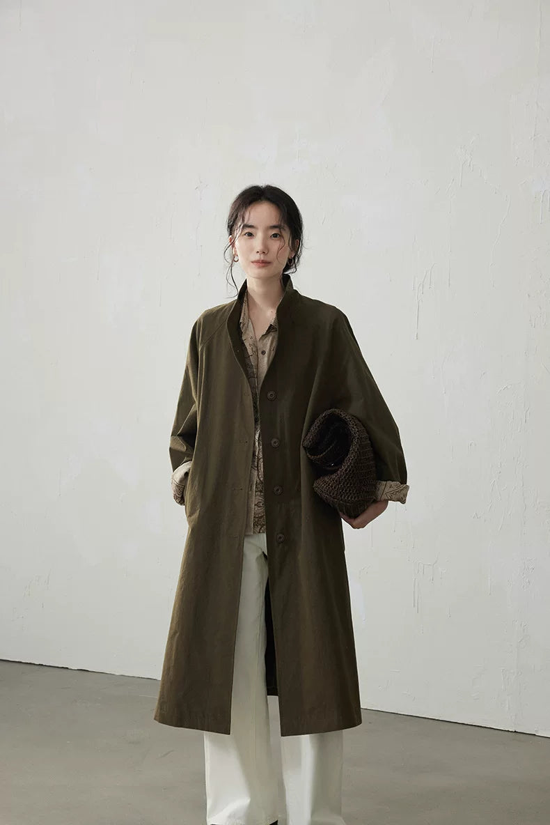 Olive longline trench coat worn open with stand collar and rolled paisley cuffs