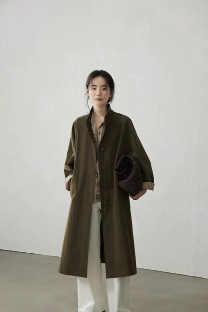 Olive longline trench coat worn open with stand collar and rolled paisley cuffs