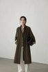 Olive longline trench coat worn open with stand collar and rolled paisley cuffs
