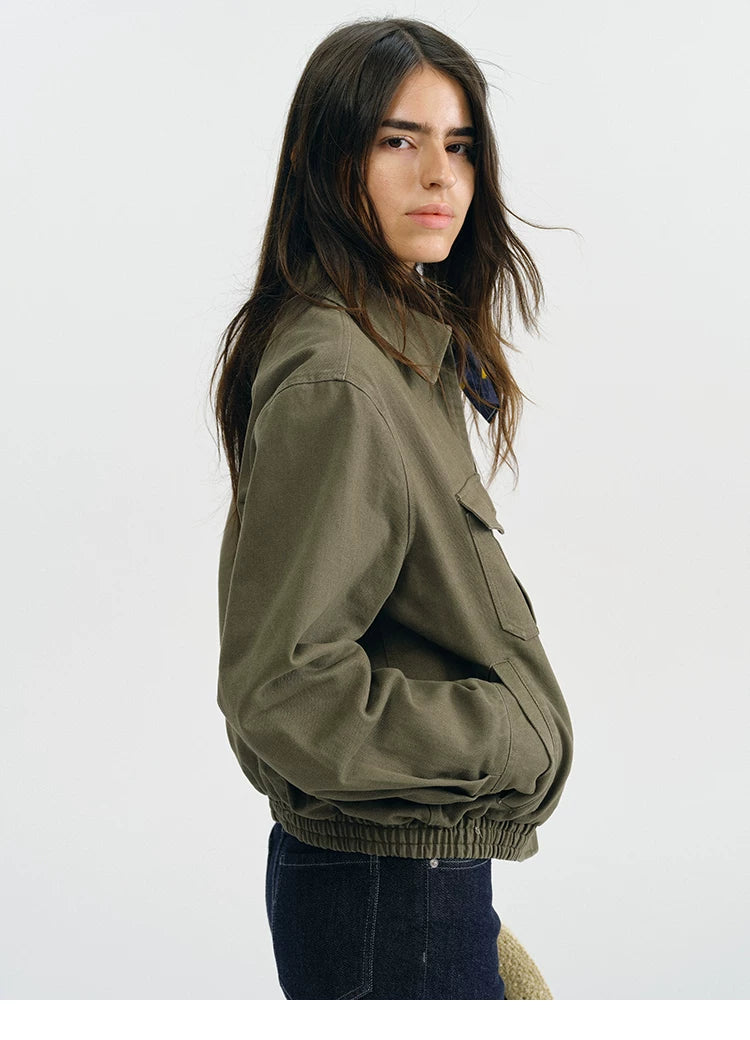 Side view of an olive utility jacket showing dropped shoulders and elastic hem