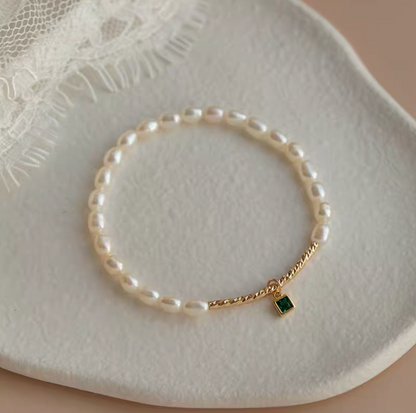 Top view of olivine pearl bracelet with square green gemstone charm and 4mm natural pearls on textured plate.
