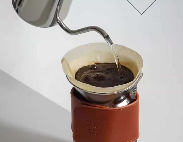 Water Silver pour over coffee set in use with hot water pouring over coffee grounds through filter cup