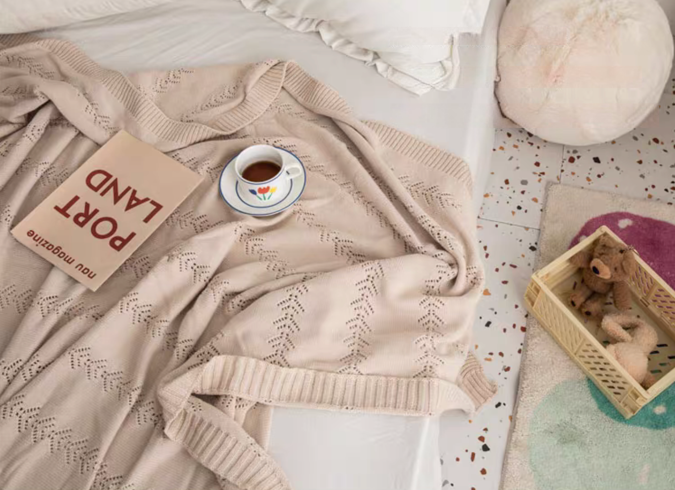 Cream White Oversize Knit Throw Blanket draped on bed with book and tea cup showing soft cotton knit pattern