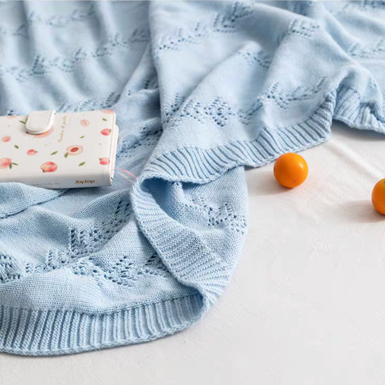Close-up of Light Blue Oversize Knit Throw Blanket with decorative knit leaf pattern and ribbed edge