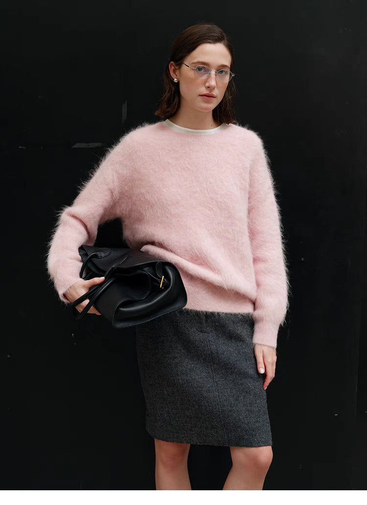 Pink oversized alpaca sweater styled with skirt in full body shot against dark background, showing relaxed fit and everyday outfit pairing