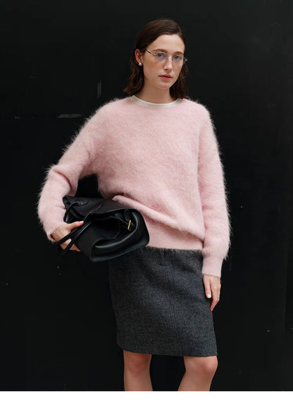 Pink oversized alpaca sweater styled with skirt in full body shot against dark background, showing relaxed fit and everyday outfit pairing