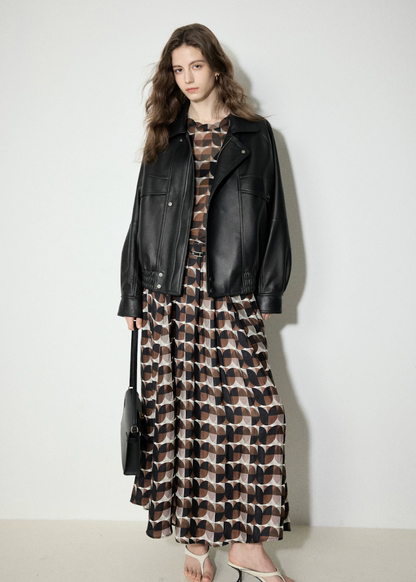 Full-length view of oversized black leather bomber worn open over a long printed dress