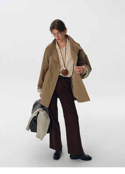 Full outfit view showing relaxed trench jacket styled with brown pants