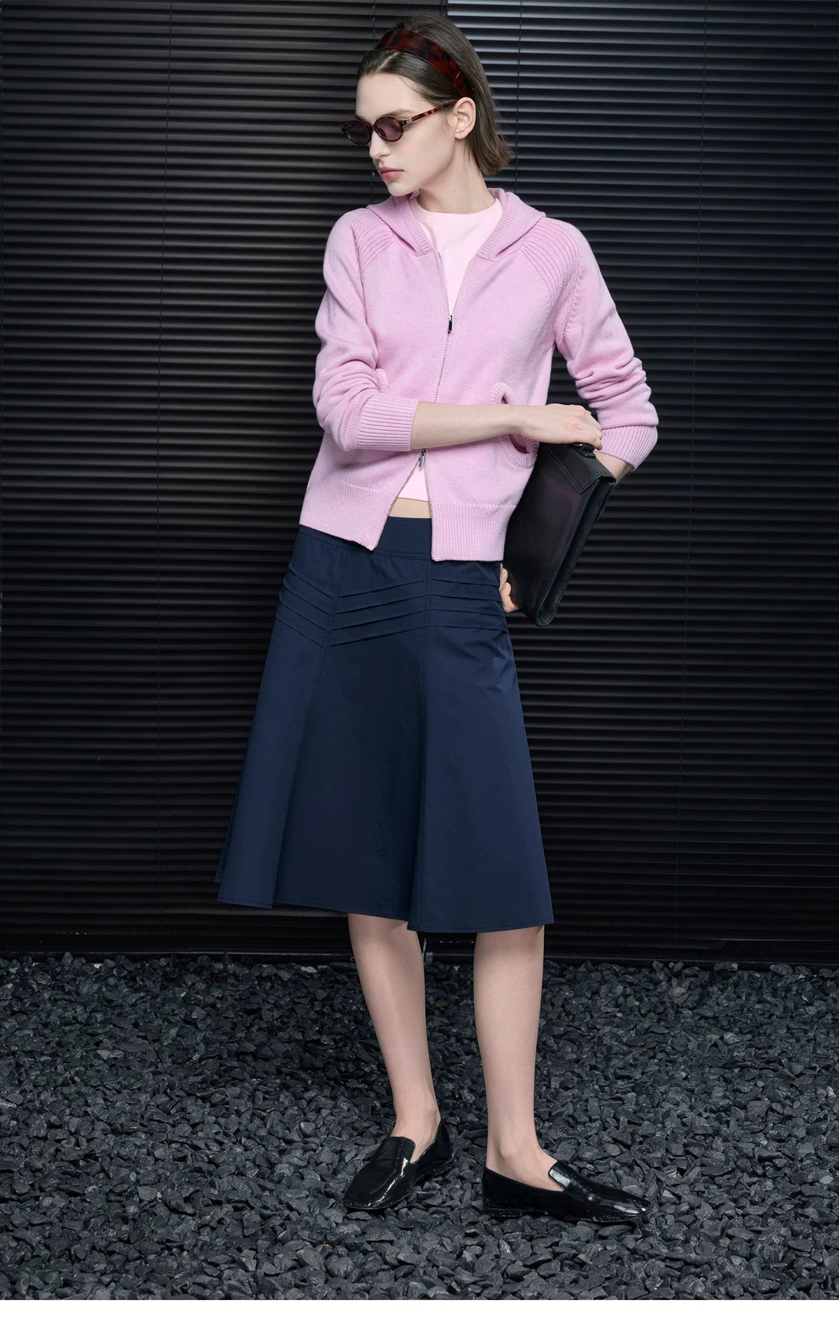 Pastel Pink hooded knit cardigan styled with a black clutch, navy midi skirt and tortoiseshell sunglasses