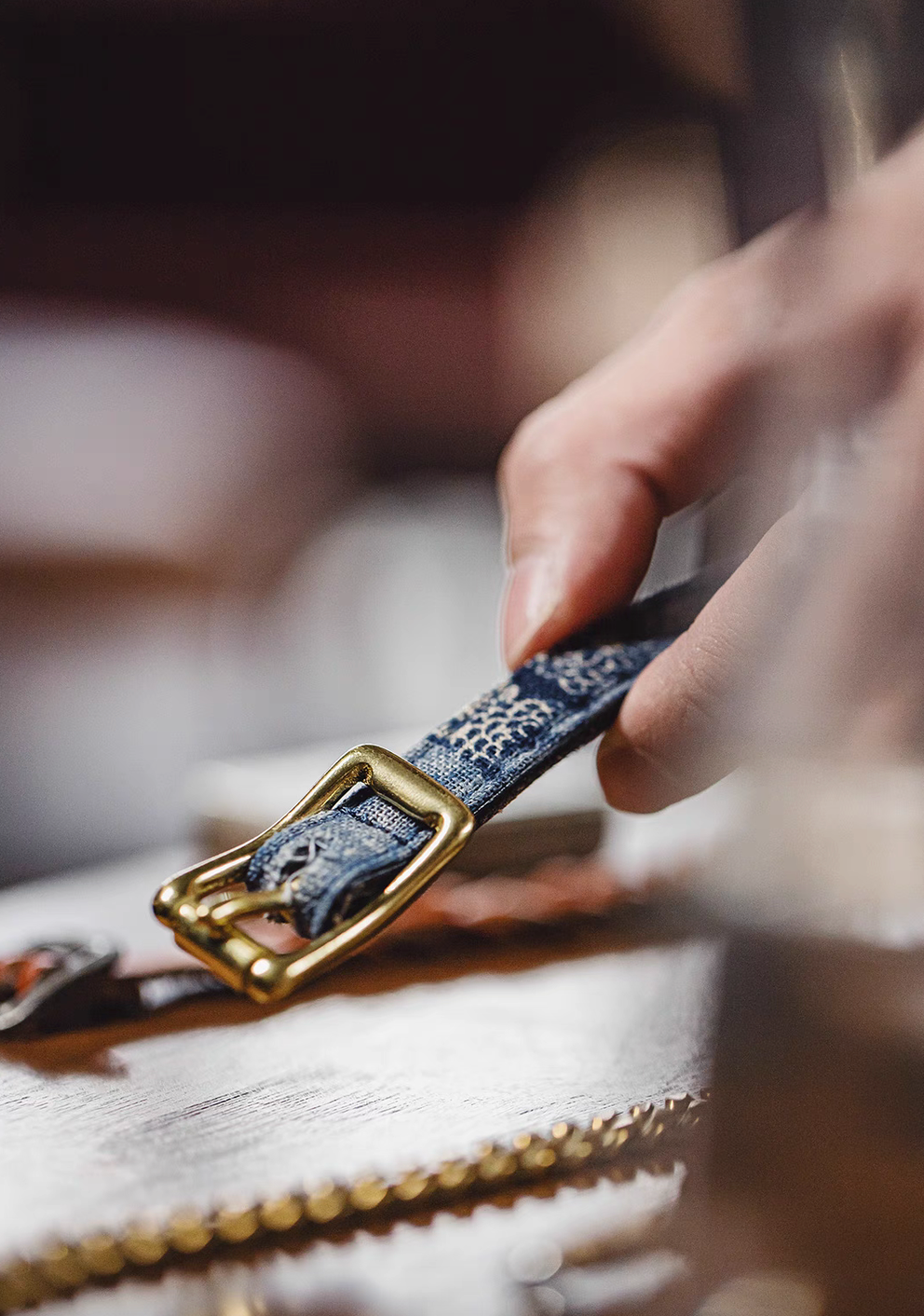 Close-up of patchwork leather bracelet with brass buckle placed on workbench highlighting craftsmanship