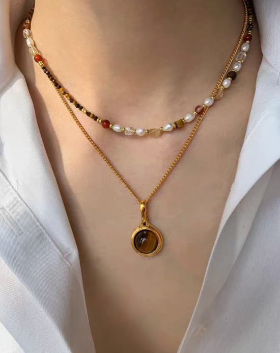 Layered look of multicolor pearl and tiger eye necklace set worn on neck with beaded choker and gold tiger eye pendant chain