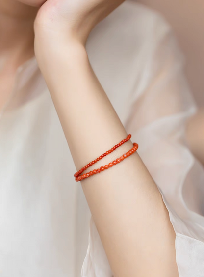 Persimmon red agate bead bracelets worn on wrist in stacked minimalist fashion look