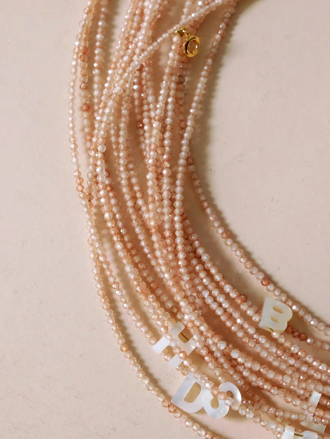 Natural color personalized shell initial necklace with delicate beaded chain and gold clasp detail close-up