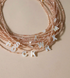 Personalized shell initial necklace with multiple pearl letter charms on beaded chain showing natural stone detail close-up