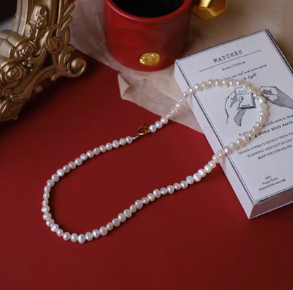 Petite baroque freshwater pearl necklace with 4 to 4.5mm pearls natural color on red background