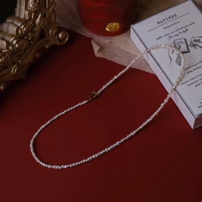 Petite 15 inch baroque freshwater pearl single strand necklace natural color flat lay on red background with clasp detail