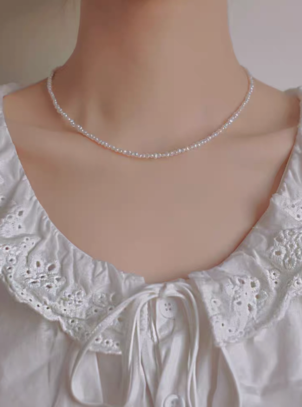 Front view of model wearing petite baroque freshwater pearl single strand necklace in natural color