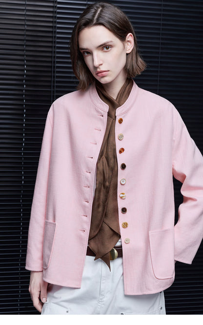 Pink linen band-collar jacket worn open, showing the mismatched button front and patch pockets