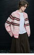 Woman wearing Pink Stripe chunky knit zip cardigan open over a white tee with brown corduroy pants