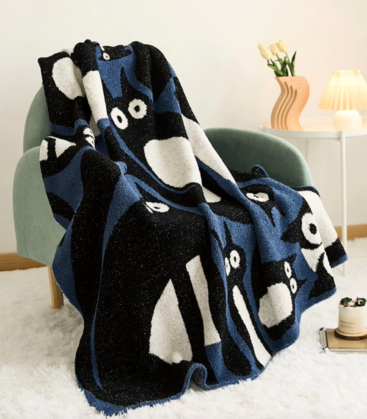 Blue and black cat blanket draped over chair in living room with lamp and flowers highlighting cozy styling