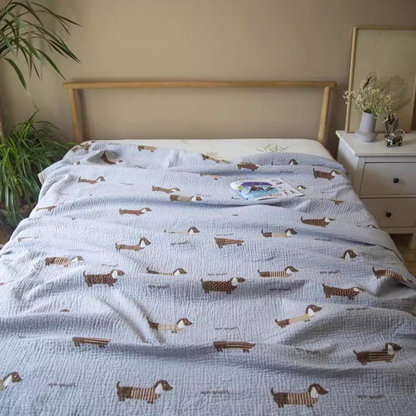 Playful Pals Cotton Gauze Quilted Blanket Puppy styled on a bed in a bright bedroom with dachshund dog print bedding