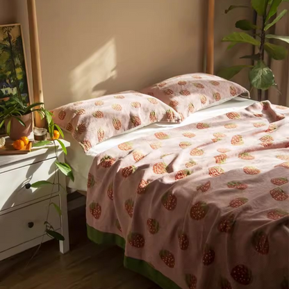 Playful Pals Cotton Gauze Quilted Blanket Strawberry styled on a cozy bedroom bed with strawberry pattern bedding and pillows